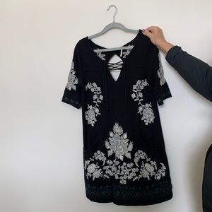 Free people black knit top with key hole and white embroidery.